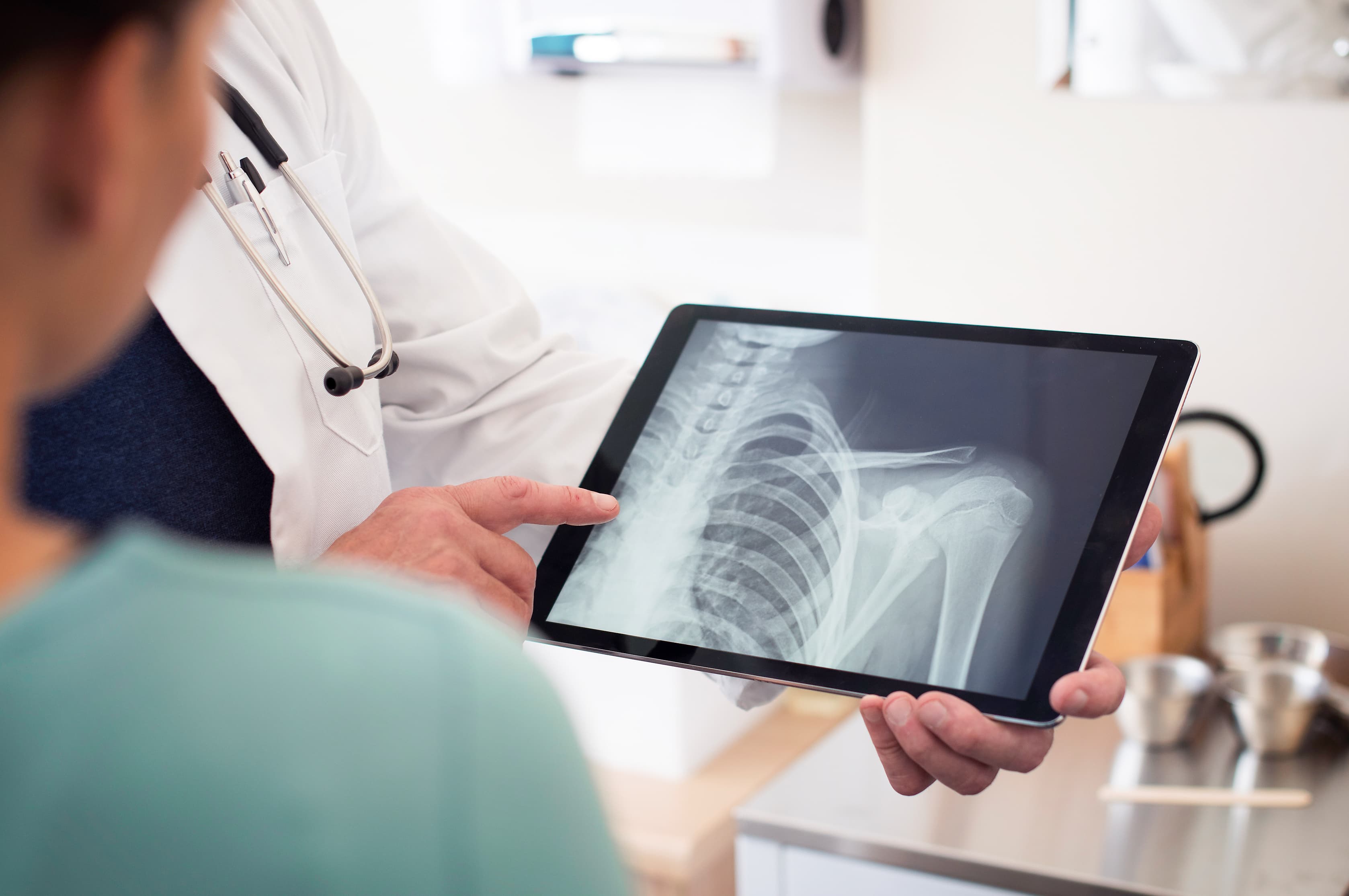 Ein Arzt zeigt einem Patienten ein Röntgenbild auf einem Tablet – sicherer digitaler Zugang zu medizinischen Untersuchungen mit Agora Care